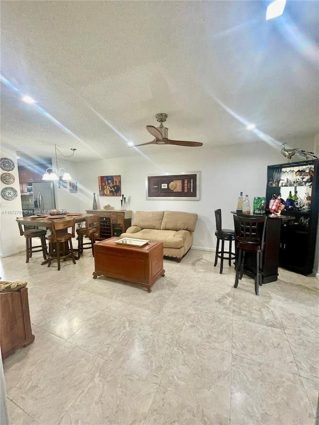 living room with a textured ceiling and ceiling fan with notable chandelier