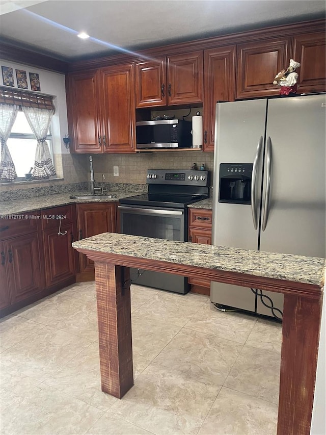 kitchen with light stone countertops, sink, stainless steel appliances, and backsplash