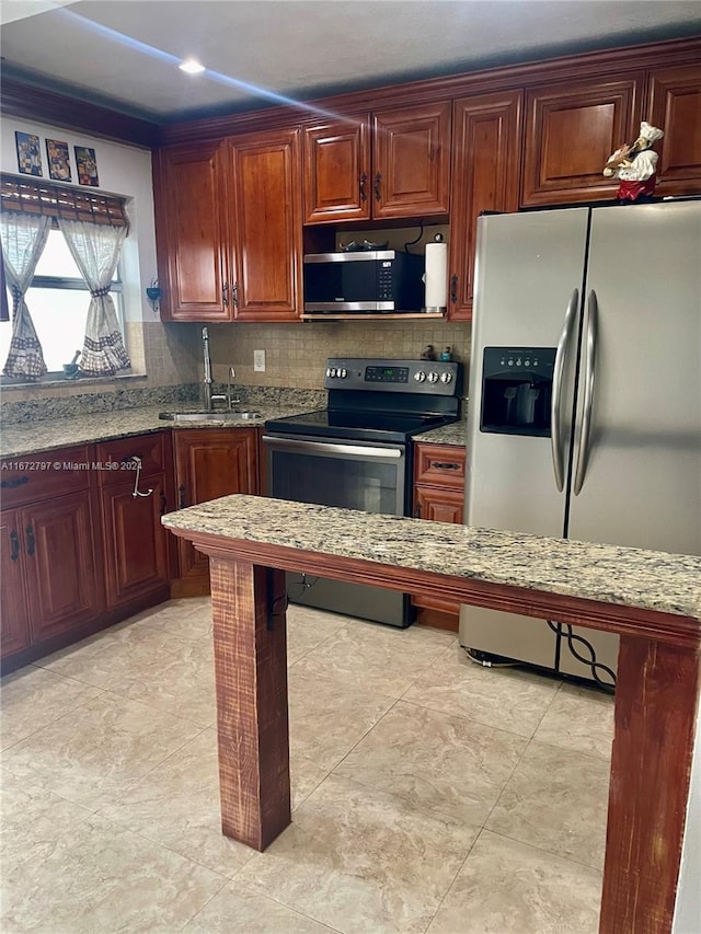 kitchen featuring light stone counters, decorative backsplash, sink, and stainless steel appliances