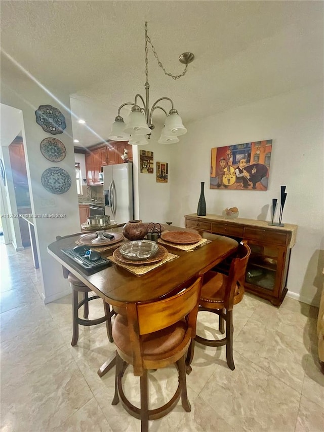 dining area with an inviting chandelier, sink, and a textured ceiling