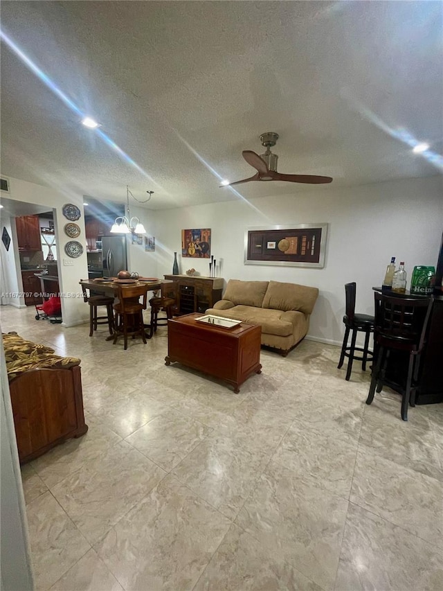 living room featuring ceiling fan and a textured ceiling