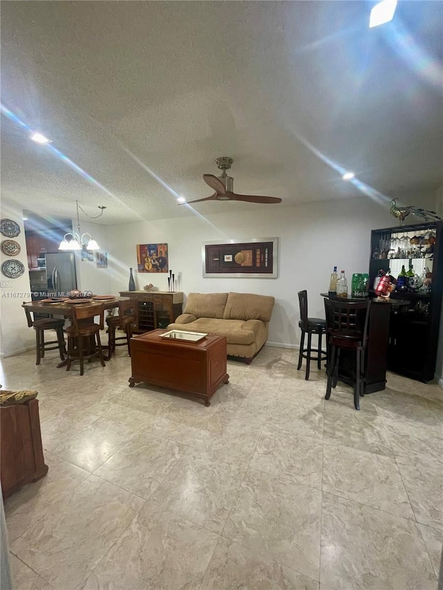 living room featuring a textured ceiling and ceiling fan with notable chandelier