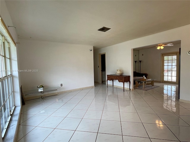 tiled spare room featuring a baseboard heating unit and ceiling fan