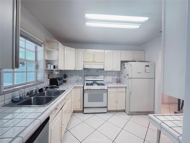 kitchen featuring tasteful backsplash, sink, white appliances, light tile patterned flooring, and tile counters