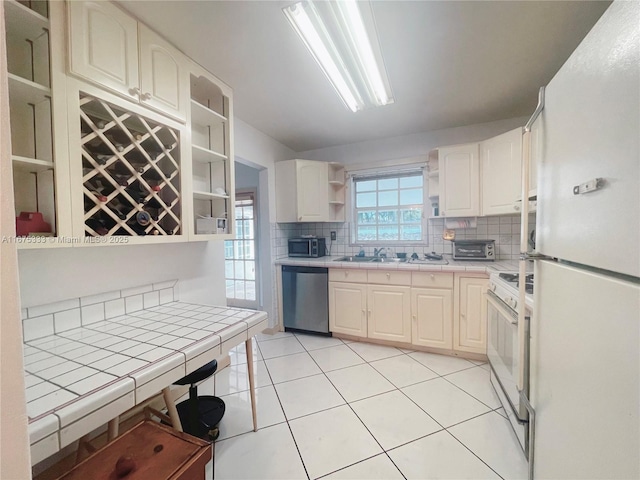 kitchen with appliances with stainless steel finishes, decorative backsplash, sink, tile countertops, and light tile patterned floors