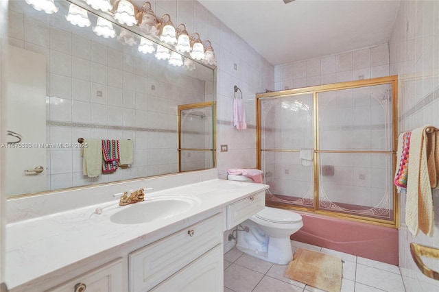 full bathroom featuring toilet, tile patterned flooring, tile walls, vanity, and shower / bath combination with glass door