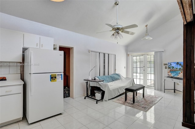 interior space with ceiling fan, vaulted ceiling, white fridge, light tile patterned floors, and french doors