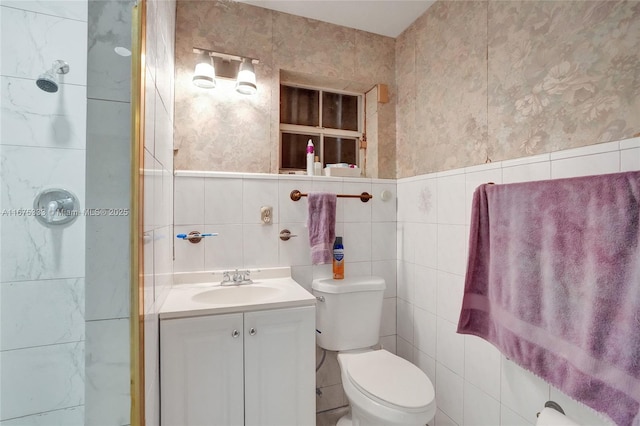 bathroom featuring toilet, vanity, and tile walls