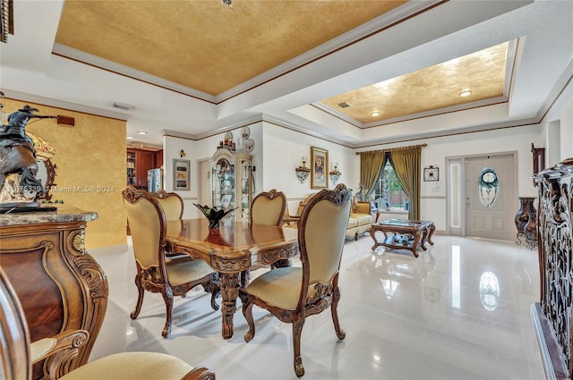 dining area with light tile patterned floors, a raised ceiling, and ornamental molding