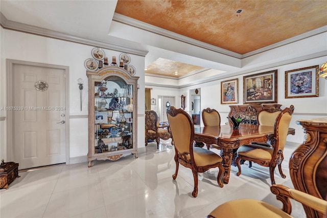 dining area with a raised ceiling, crown molding, and light tile patterned floors