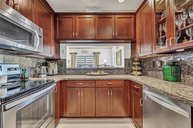 kitchen with stainless steel appliances, light stone countertops, decorative backsplash, and light tile patterned floors