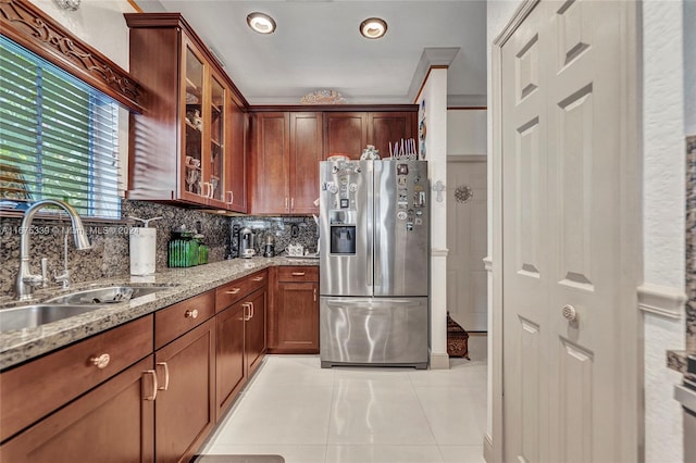 kitchen featuring light stone counters, tasteful backsplash, sink, crown molding, and stainless steel refrigerator with ice dispenser