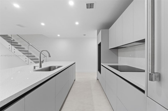 kitchen with black electric cooktop, white cabinets, and sink