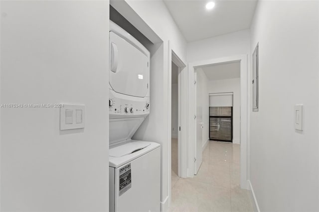 laundry area with light tile patterned flooring and stacked washer / dryer