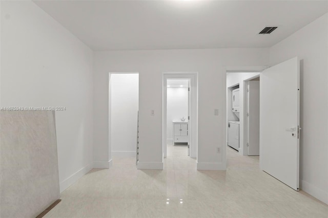 unfurnished bedroom featuring stacked washer / dryer and ensuite bathroom