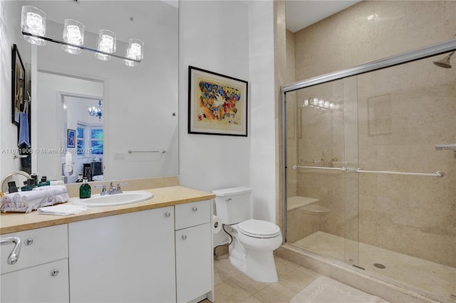 bathroom featuring tile patterned flooring, vanity, a shower with door, and toilet