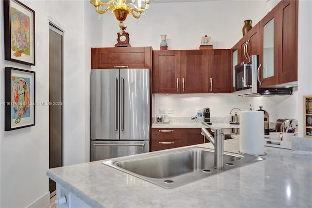 kitchen with stainless steel appliances, hanging light fixtures, sink, and an inviting chandelier