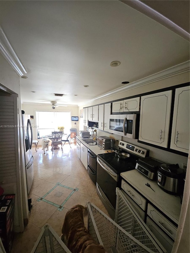 kitchen featuring light tile patterned flooring, sink, white cabinetry, appliances with stainless steel finishes, and crown molding