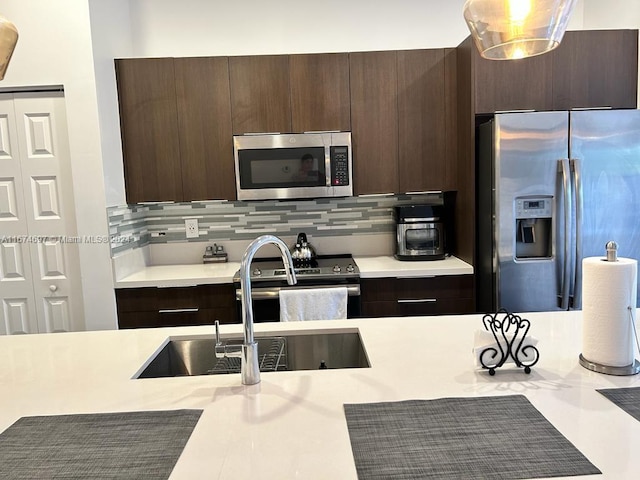 kitchen with appliances with stainless steel finishes, dark brown cabinetry, decorative backsplash, and sink