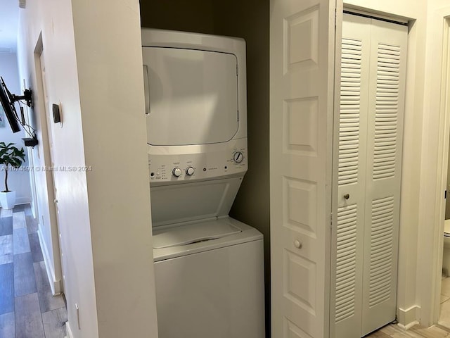 laundry room featuring stacked washer and clothes dryer and light hardwood / wood-style flooring