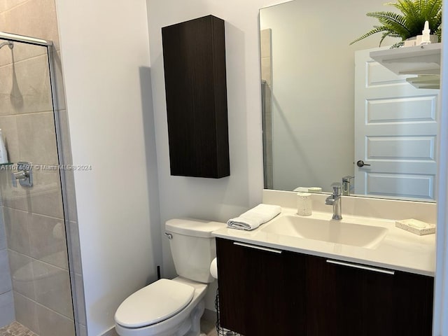 bathroom featuring a shower with shower door, vanity, and toilet