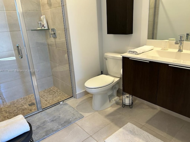 bathroom featuring tile patterned flooring, a shower with door, vanity, and toilet