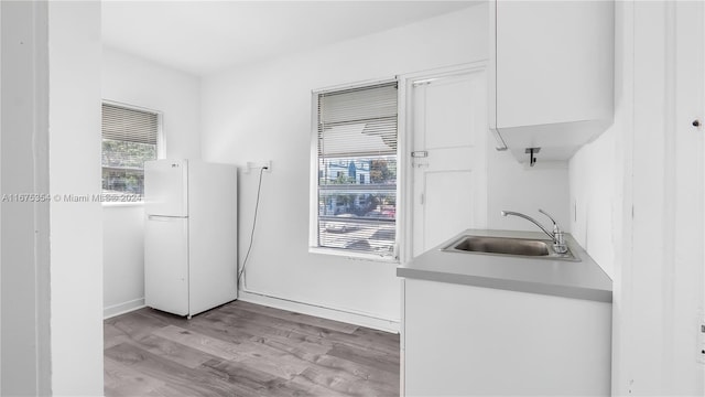 kitchen featuring white fridge, white cabinets, sink, and light wood-type flooring