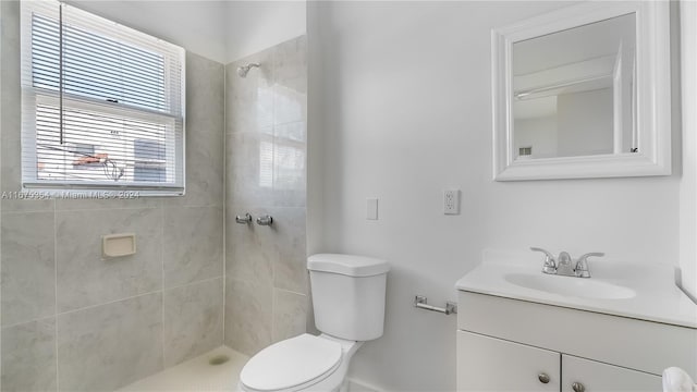 bathroom with a tile shower, vanity, and toilet