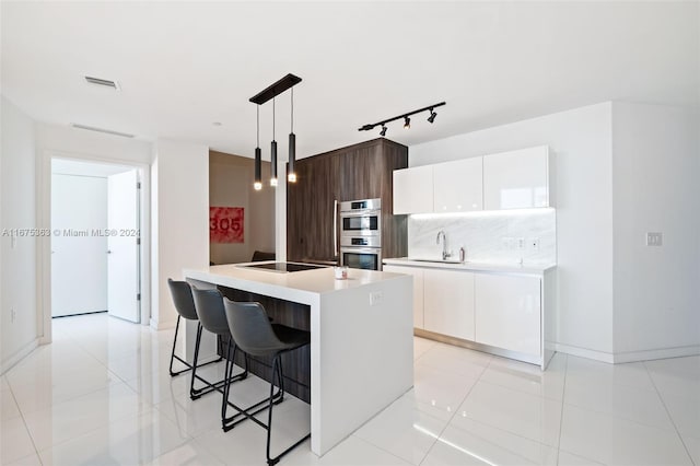 kitchen featuring dark brown cabinets, white cabinetry, a kitchen island with sink, pendant lighting, and stainless steel double oven