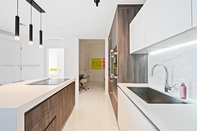 kitchen with white cabinets, light tile patterned floors, black electric cooktop, pendant lighting, and sink