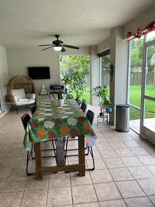 tiled dining room with ceiling fan and a textured ceiling