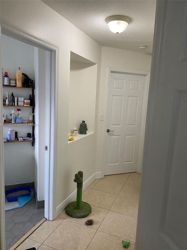 hallway with light tile patterned flooring and a textured ceiling