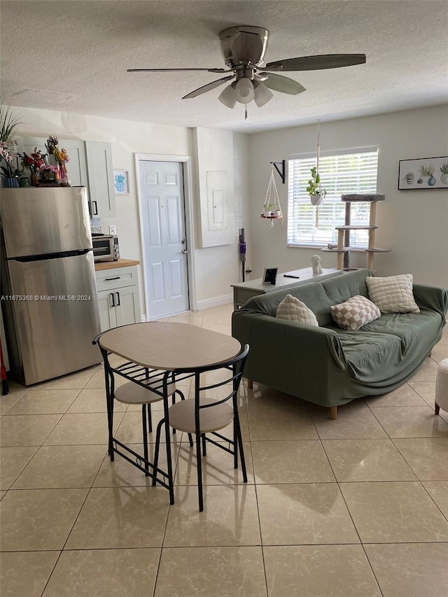 dining space featuring light tile patterned flooring, ceiling fan, and a textured ceiling