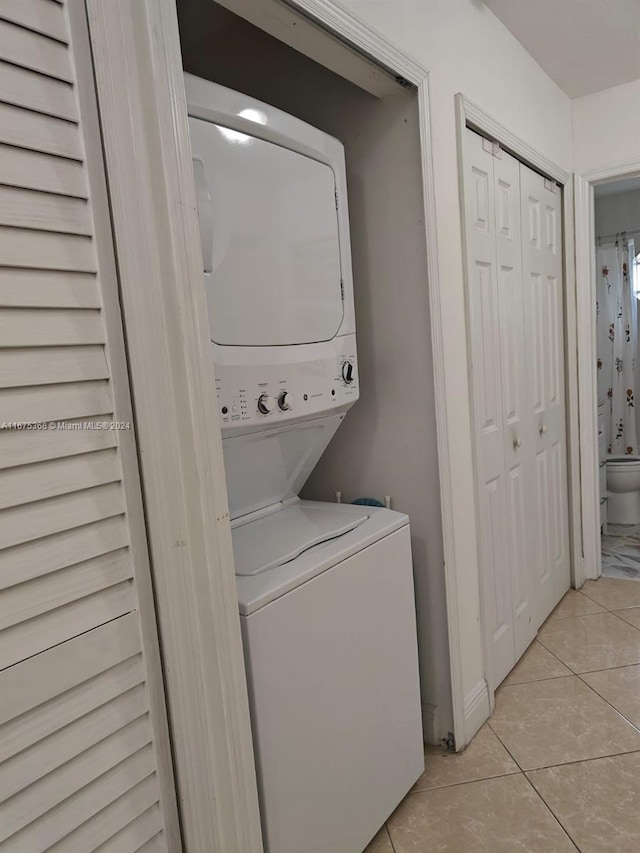 laundry room with stacked washer / dryer and light tile patterned floors