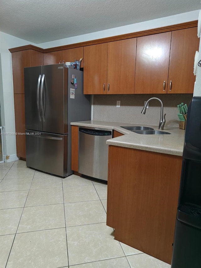 kitchen featuring appliances with stainless steel finishes, sink, light tile patterned floors, and a textured ceiling