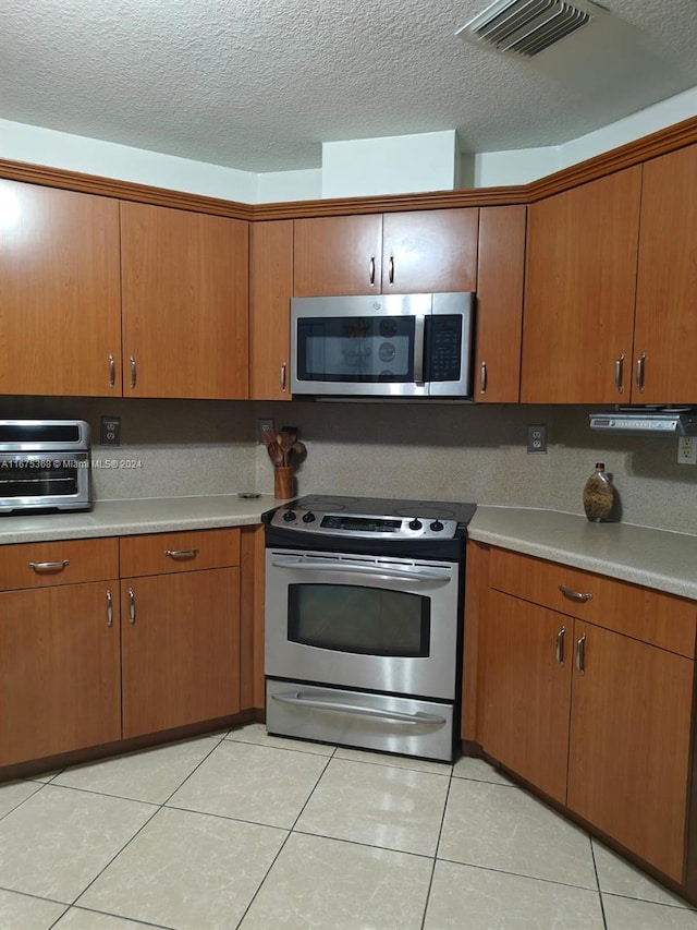 kitchen with light tile patterned flooring, stainless steel appliances, and a textured ceiling