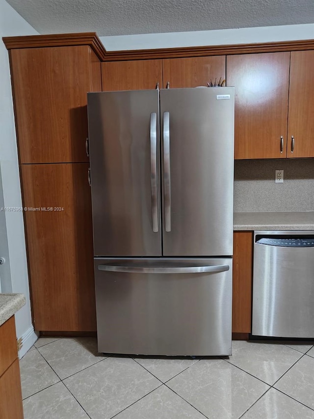 kitchen with a textured ceiling, stainless steel appliances, and light tile patterned floors