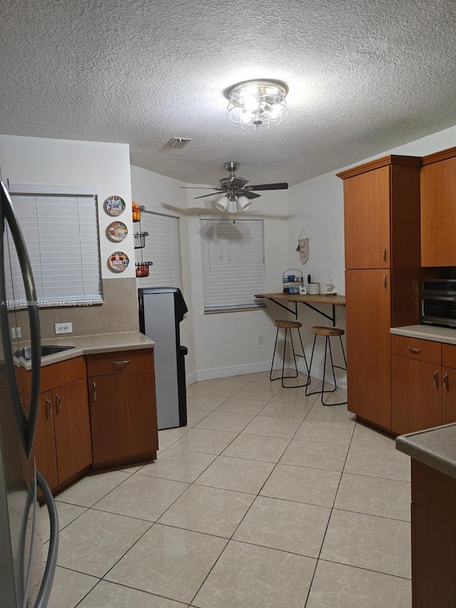 kitchen featuring ceiling fan, light tile patterned floors, and a textured ceiling