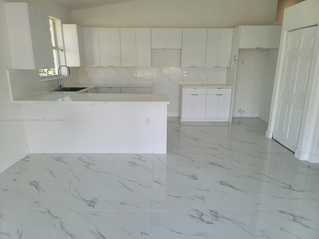 kitchen featuring vaulted ceiling, sink, and white cabinetry