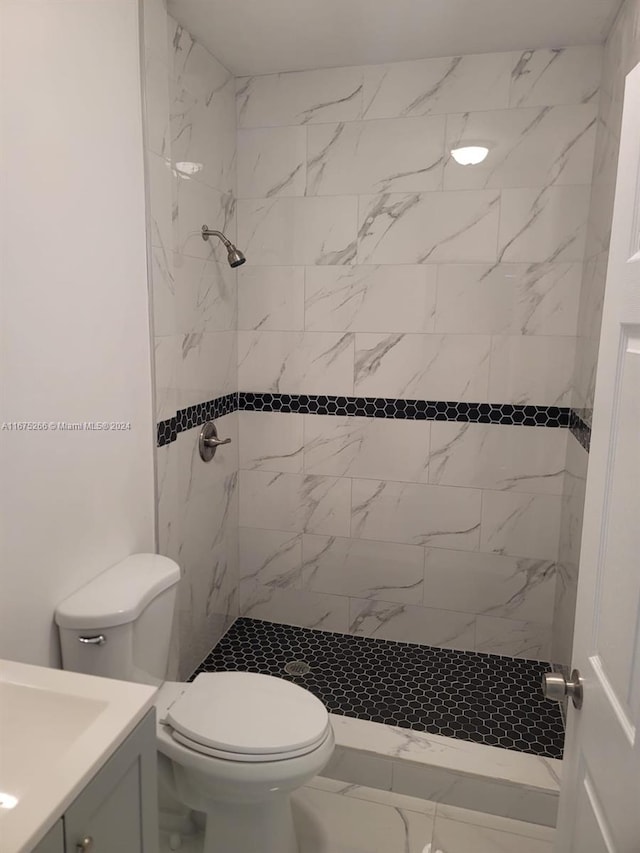 bathroom with vanity, toilet, and tiled shower