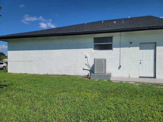 rear view of house featuring central AC and a lawn