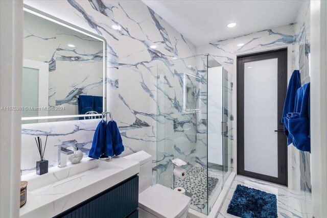 bathroom with tile walls, a shower with shower door, vanity, and toilet