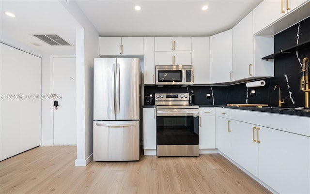 600 Three Islands Blvd Unit 214, Hallandale Beach, FL 33009 - kitchen featuring appliances with stainless steel finishes, dark countertops, tasteful backsplash, light wood-type flooring, and white cabinetry