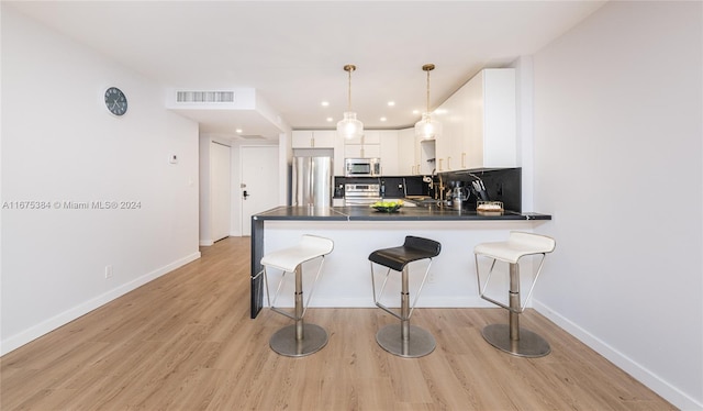 600 Three Islands Blvd Unit 214, Hallandale Beach, FL 33009 - kitchen featuring stainless steel appliances, dark countertops, a peninsula, white cabinets, and a breakfast bar area