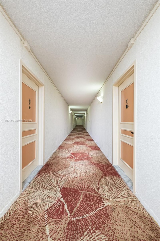 600 Three Islands Blvd Unit 214, Hallandale Beach, FL 33009 - hallway with a textured ceiling, a textured wall, carpet floors, and built in shelves