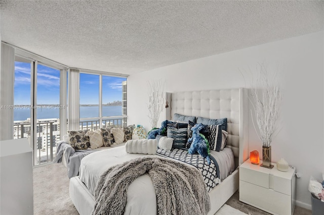 carpeted bedroom featuring a textured ceiling, a wall of windows, access to exterior, and a water view