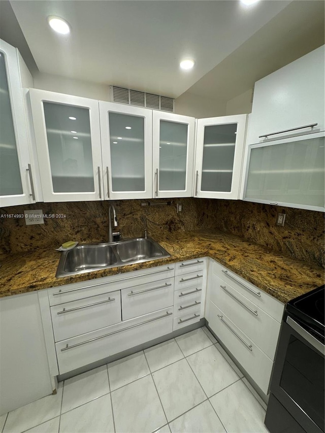 kitchen with dark stone countertops, decorative backsplash, sink, and white cabinets