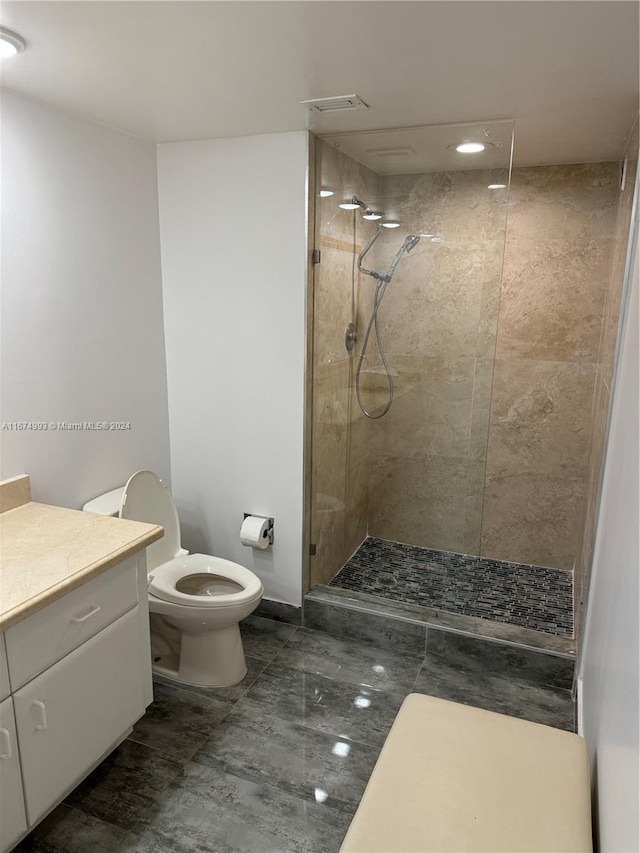 bathroom with vanity, toilet, and tiled shower