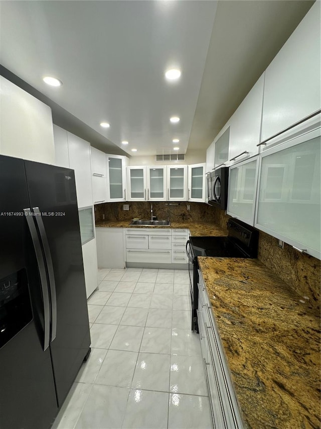 kitchen with light tile patterned floors, sink, tasteful backsplash, white cabinetry, and black appliances