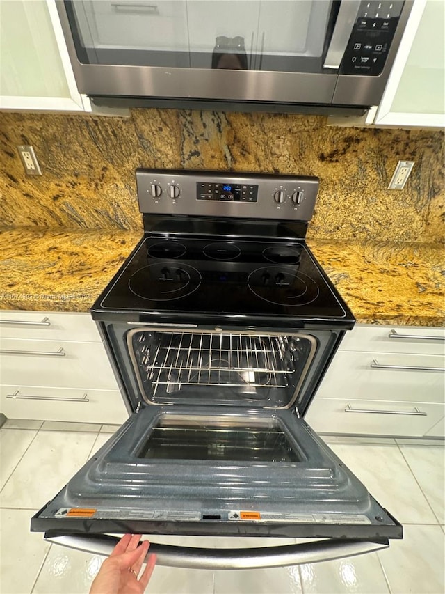 interior details featuring dark stone countertops, stainless steel appliances, tile patterned floors, and decorative backsplash